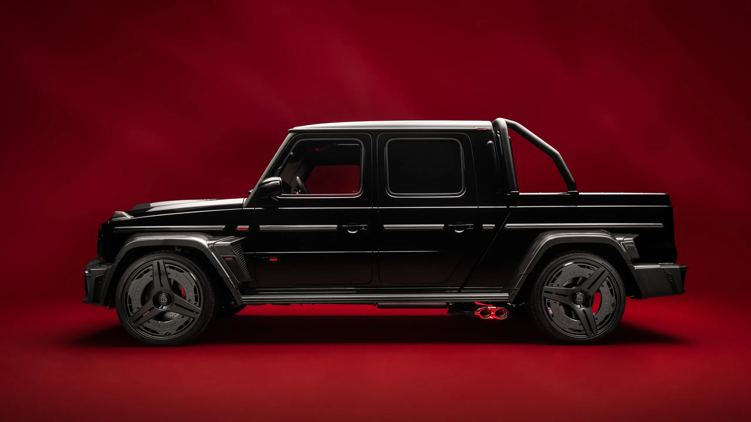 Black luxury SUV with stylish wheels against a red background.